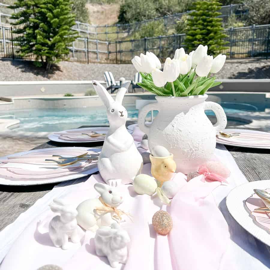 Poolside Brunch Easter Table Setting with White bunnies and white tulips on a pink table runner.