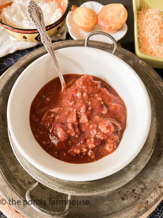 Easy Winter Chili recipe served with sour cream, shredded cheese and sweet corn bread muffins.  