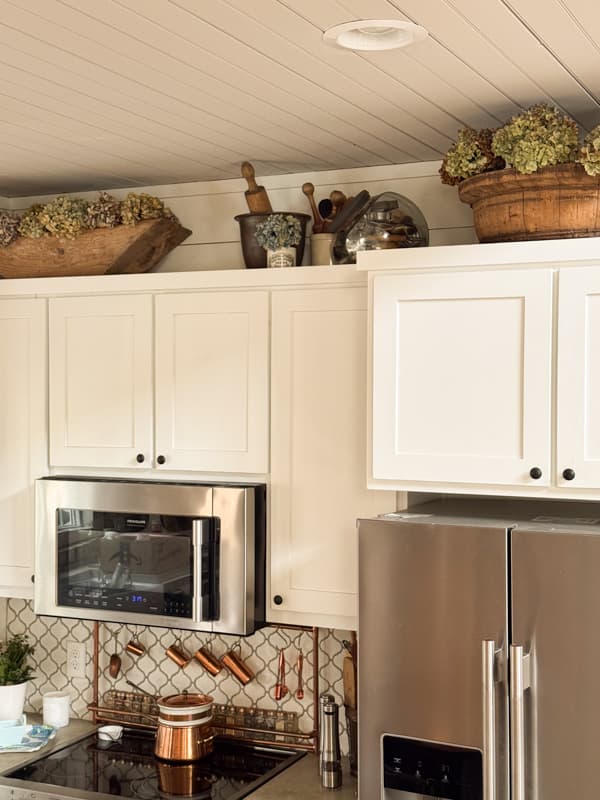 dried hydrangeas in vintage dough bowl and wooden bowl on top of kitchen cabinets