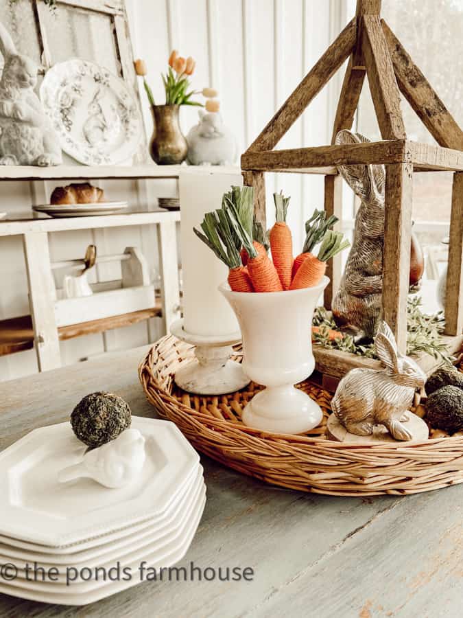 Stack of white ironstone plates and milk glass vase with Dollar Tree Carrots for a farmhouse porch centerpiece.