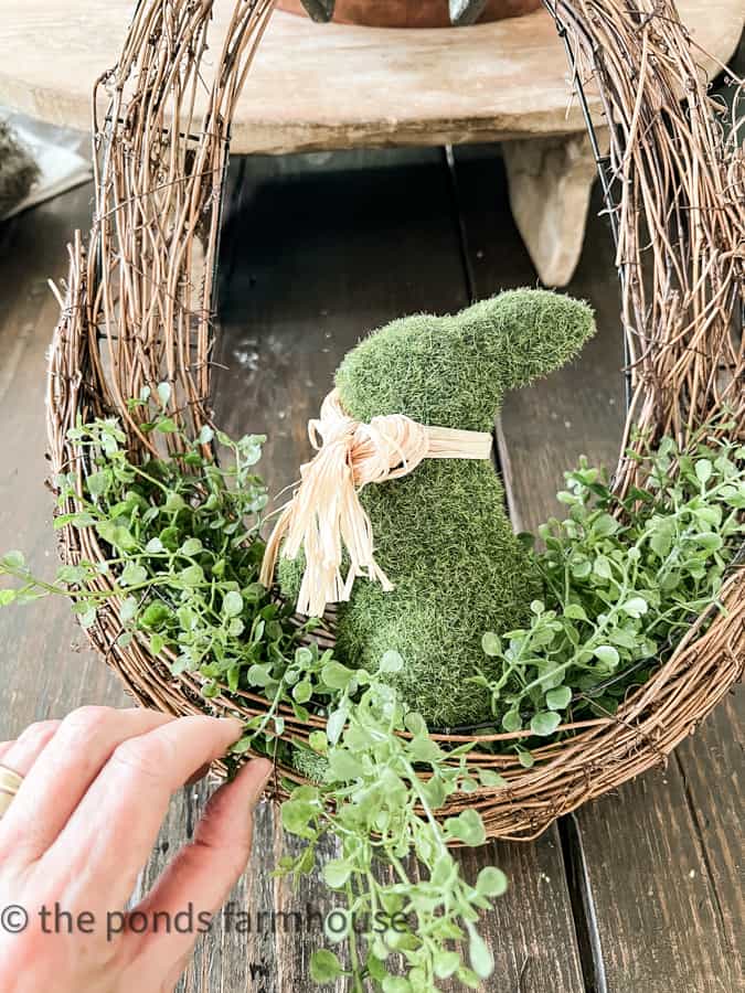 Add a moss bunny to the oval shaped wreath with greenery.  Easy tutorial for a Spring Wreath and Easter Wreath DIY
