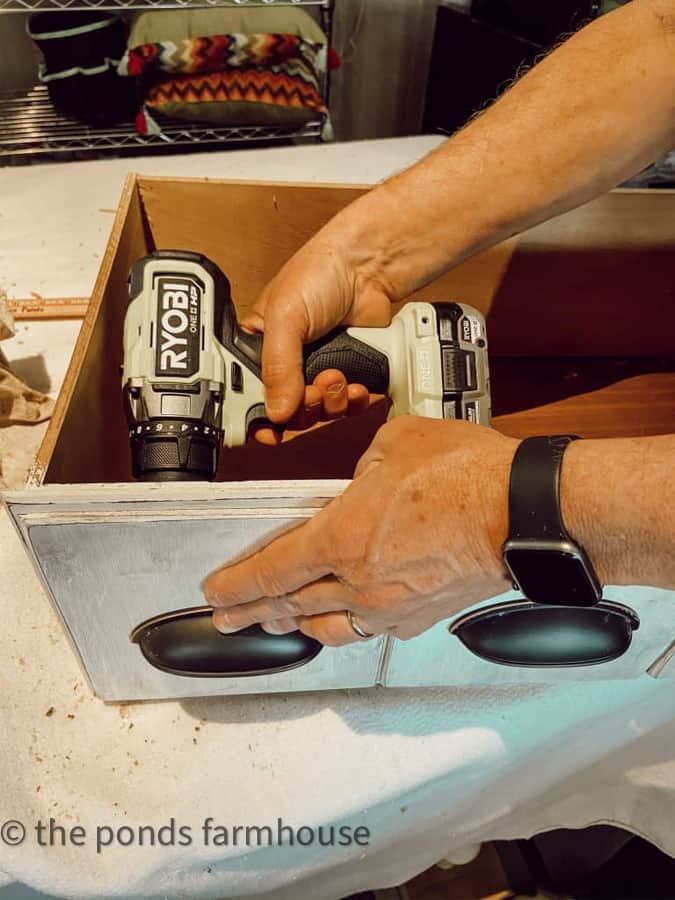 Attach new hardware to drawers on the furniture makeover project.