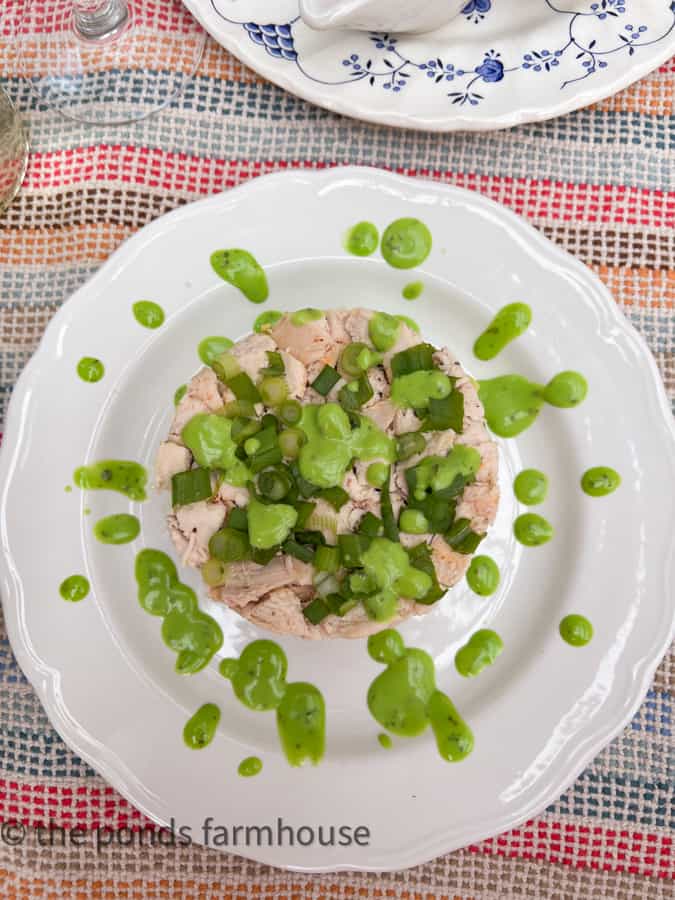 Cobb Salad with Chicken Layered Salad Recipe on white plate decorated with green salad dressing.