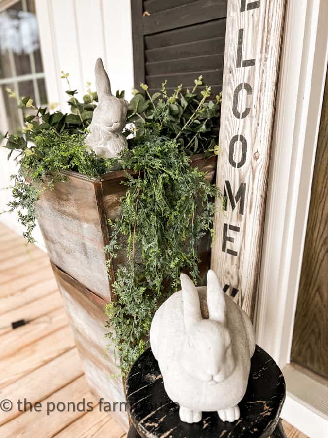 Concrete Bunnies and DIY Planters with faux greenery brighten the front porch for Spring.