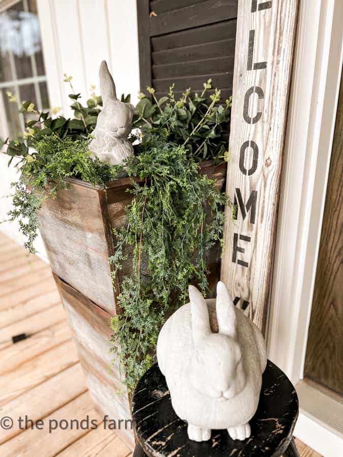 Two concrete bunny statues on front porch.