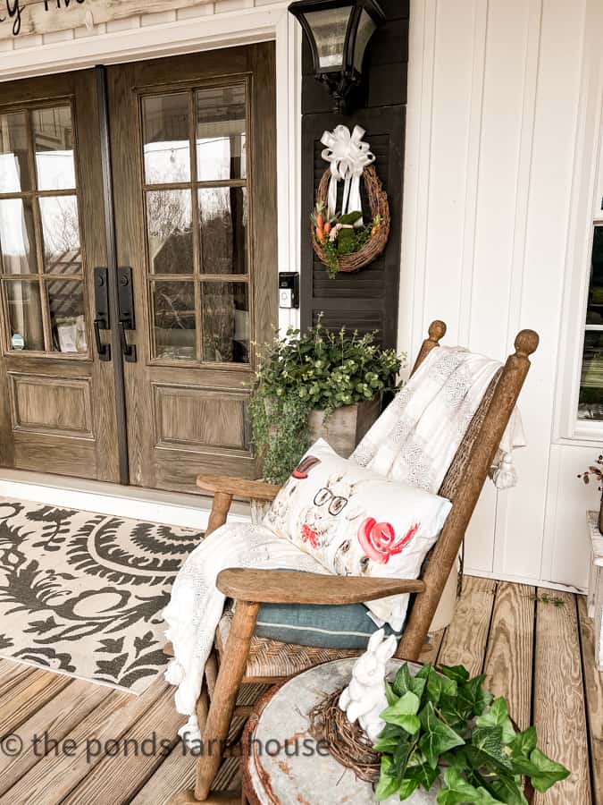 Rocking chair with fun bunny pillow and DIY Wreath for Spring decorating on the farmhouse front porch.