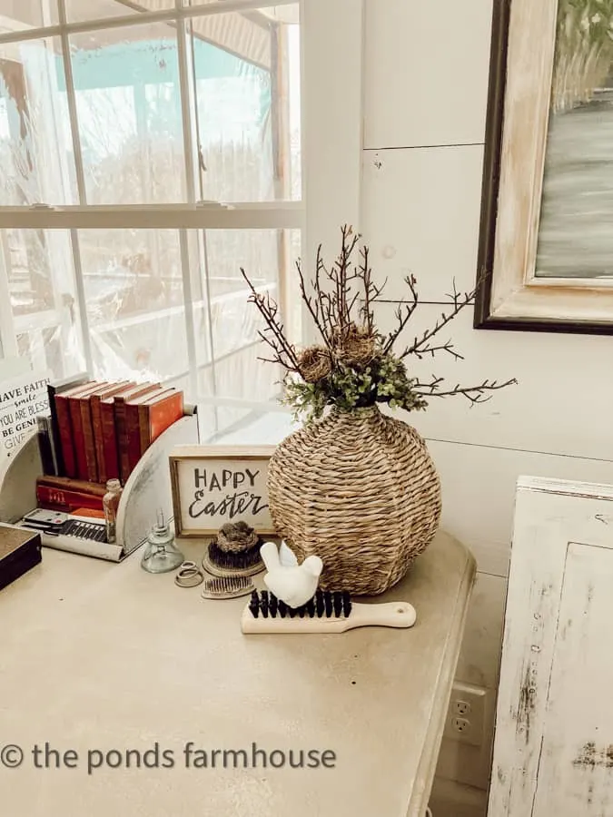 Office desk with woven seas grass vase with bird nest and greenery.  