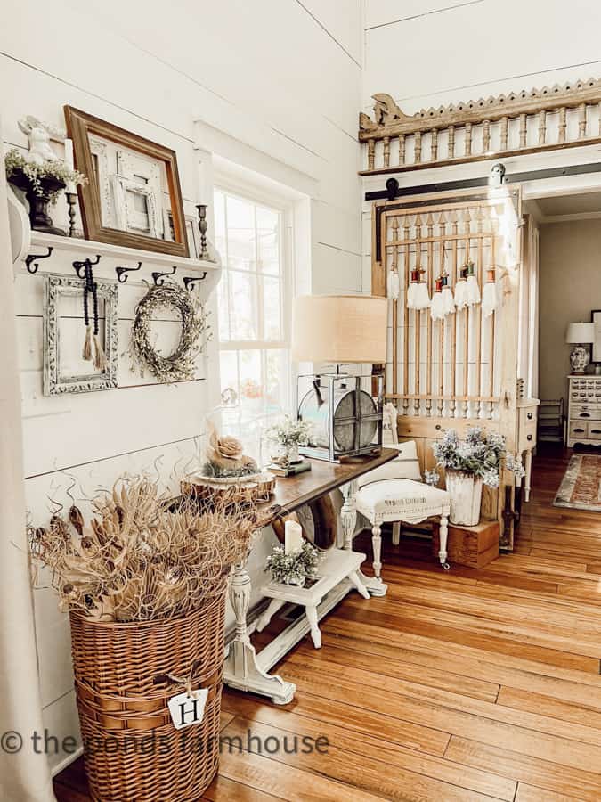 Country Chic Entry Area with Antique Barn Door and stacked vintage picture frames on wall shelf.  Repurposed Gas can lamp.