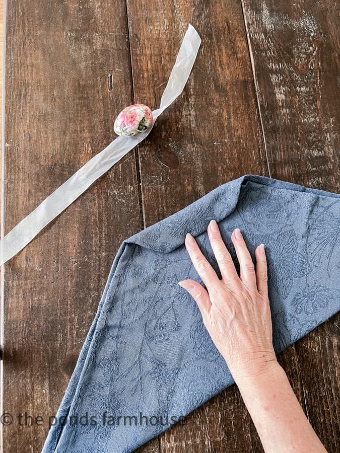 Fold napkin to male a bunny ear napkin fold for Easter with eggs and ribbon. 