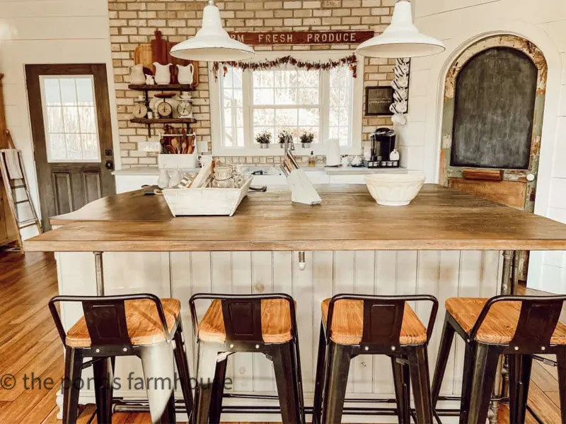 Neutral Industrial style kitchen island in open modern farmhouse  with brick wall.  Low back bar stools at eat in island.