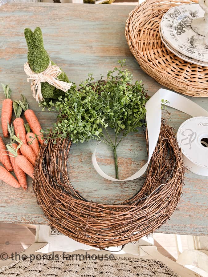Supplies for Easter Wreath DIY - grapevine wreath, carrots, greenery, bunny and ribbon. 