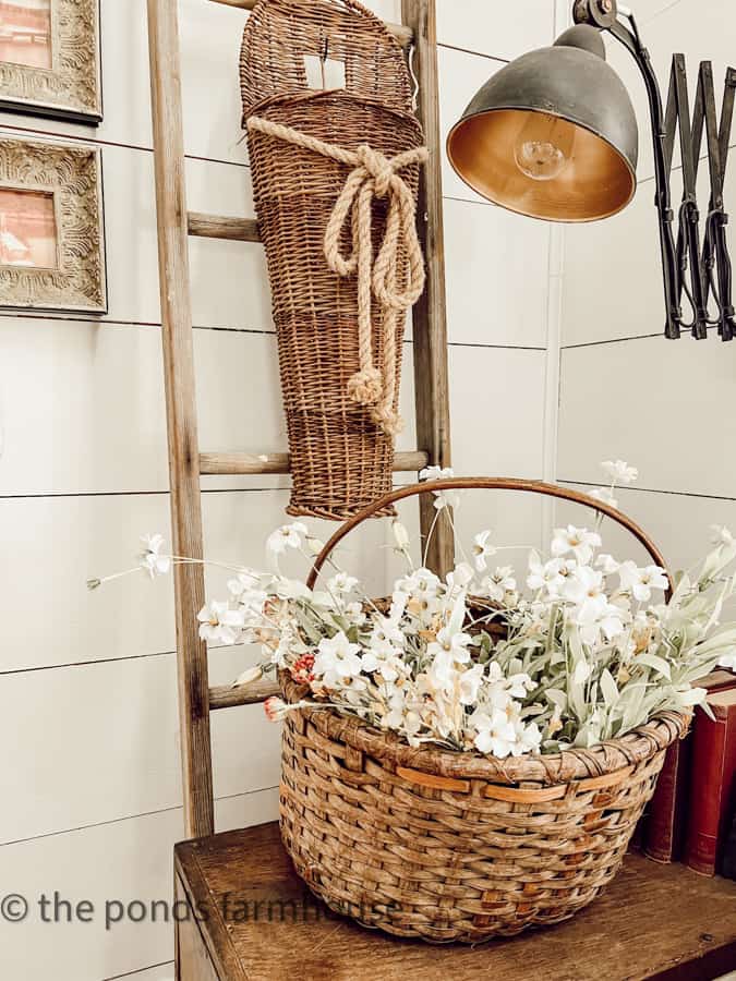 The basket hanging on old ladder and a thrifted basket filled with spring flowers in corner of office.