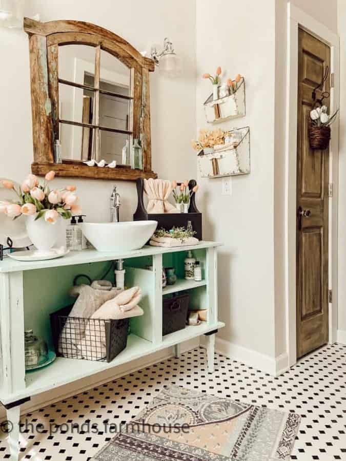 New rug on vintage black and white tile floors, vintage turquoise cabinet for vanity with pink decor.