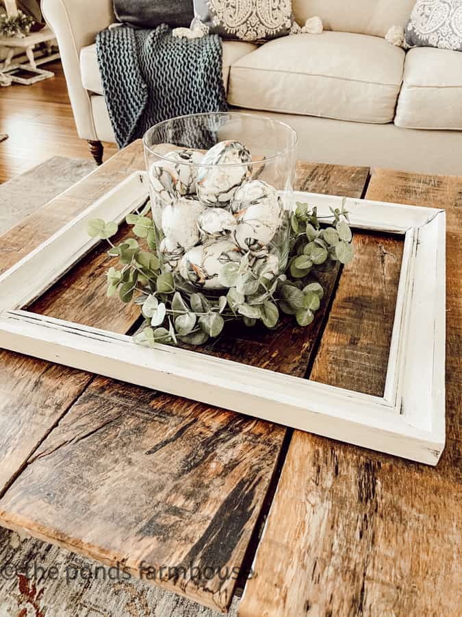 Lay an art frame on the coffee table and fill it with your vignette decor for a unique decorating idea.