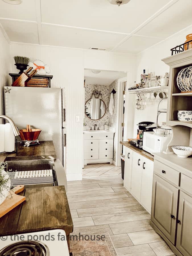 Tiny house remodel for beach cottage  small bather with updated vanity and round rattan mirro. new hardware &  faux finish like wallpaper idea.