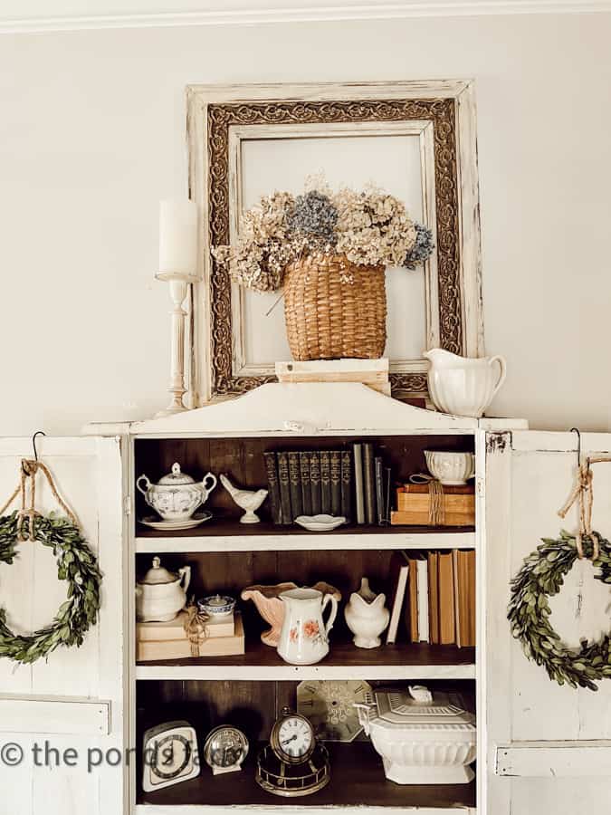 Place a vintage frame on a cabinet top and set a dried flower basket in front of the frame to instant art.