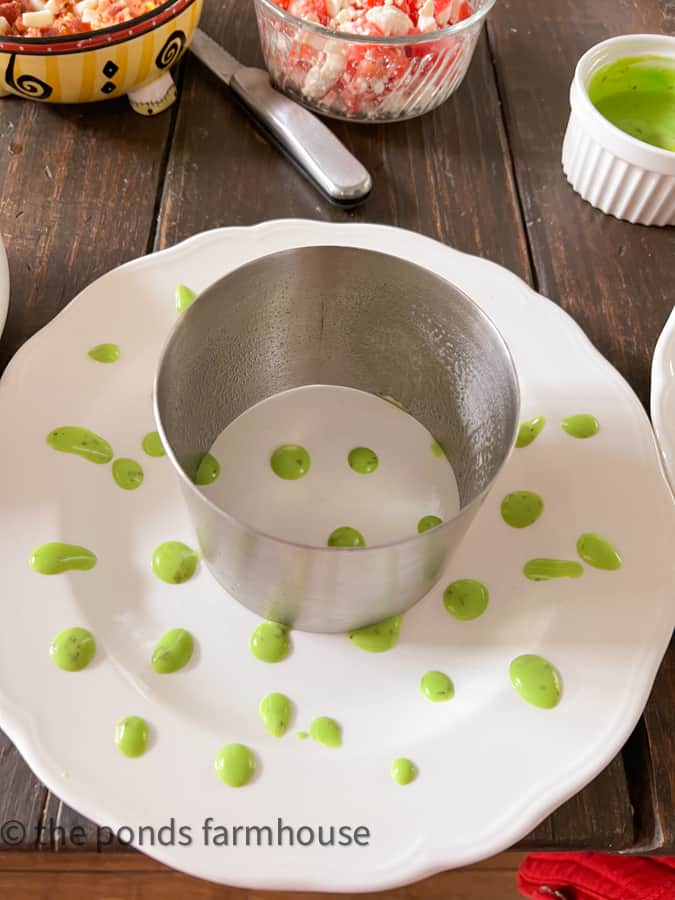 White Dinner Plate with green salad dressing and a metal small cake mold to make a stacked salad.