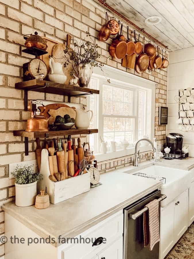 Farmhouse kitchen with open shelving, vintage copper pots, concrete countertops and farmhouse sink. 