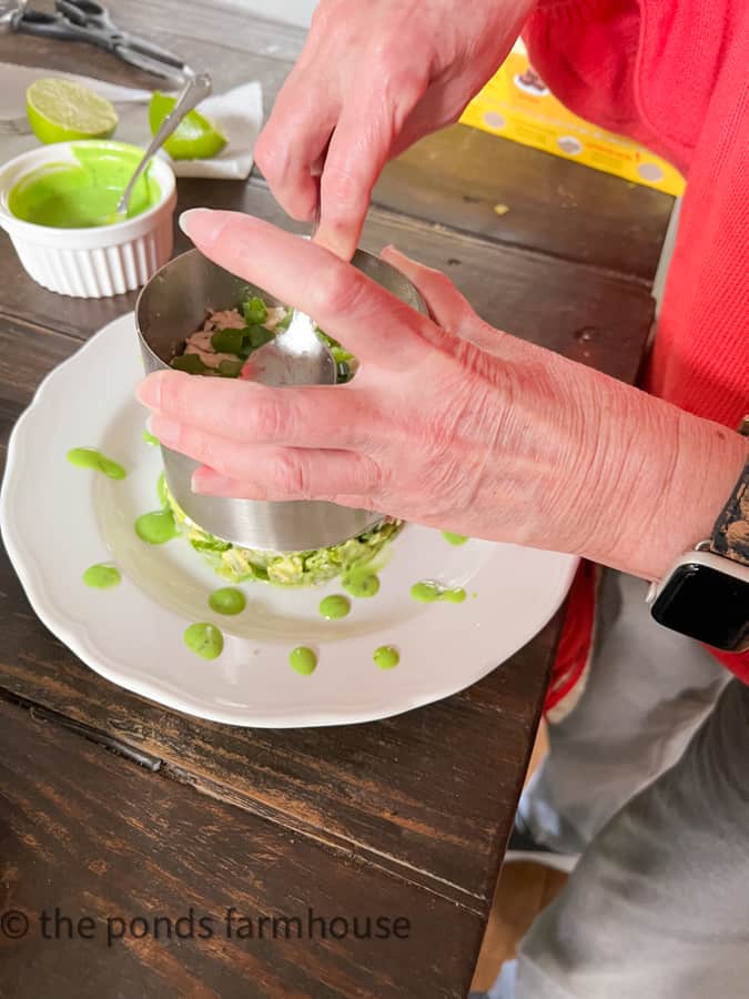 Remove mold from the stacked Salad filled with ingredients for Cobb Salad with Chicken