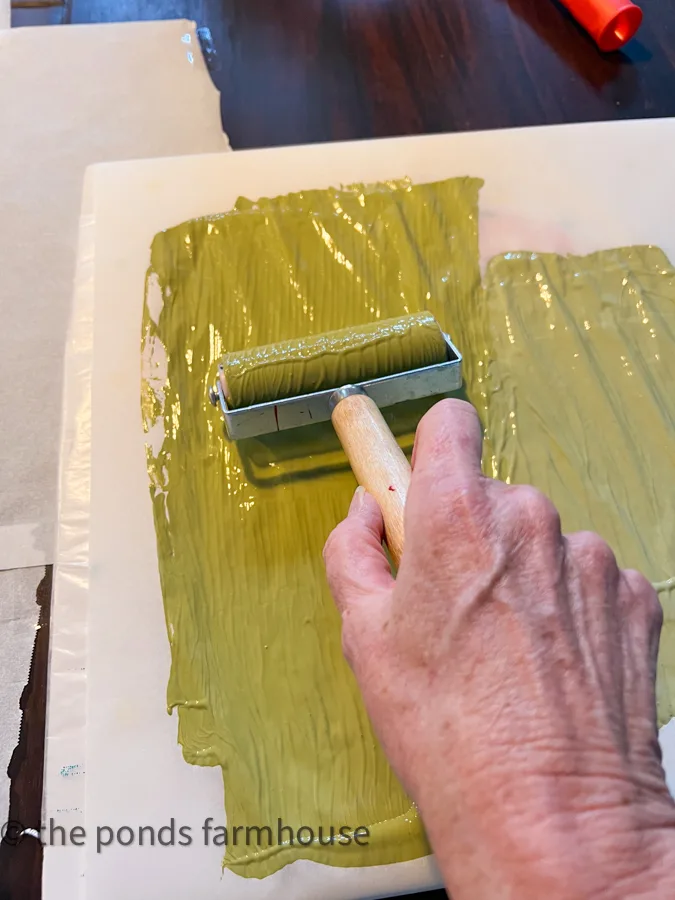 Roll paint to flatten before applying with a decorative paint roller. Two shades of green paint for custom linens