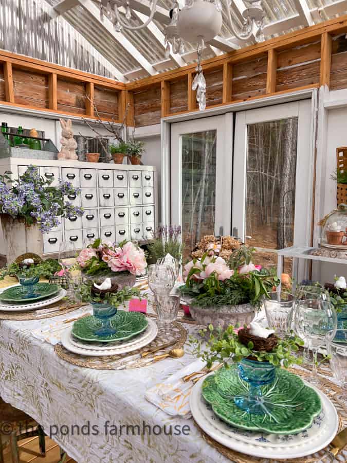 Outdoor table decor using custom painted table cloth and napkins in a greenhouse spring fling party.