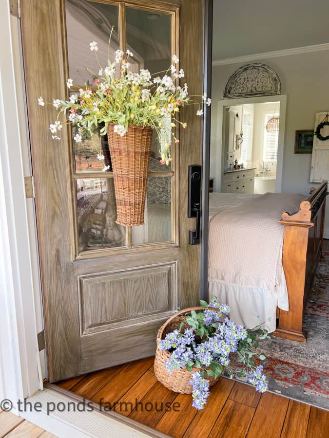 Bedroom door leading to porch sitting area with vintage baskets filled with flowers. 
