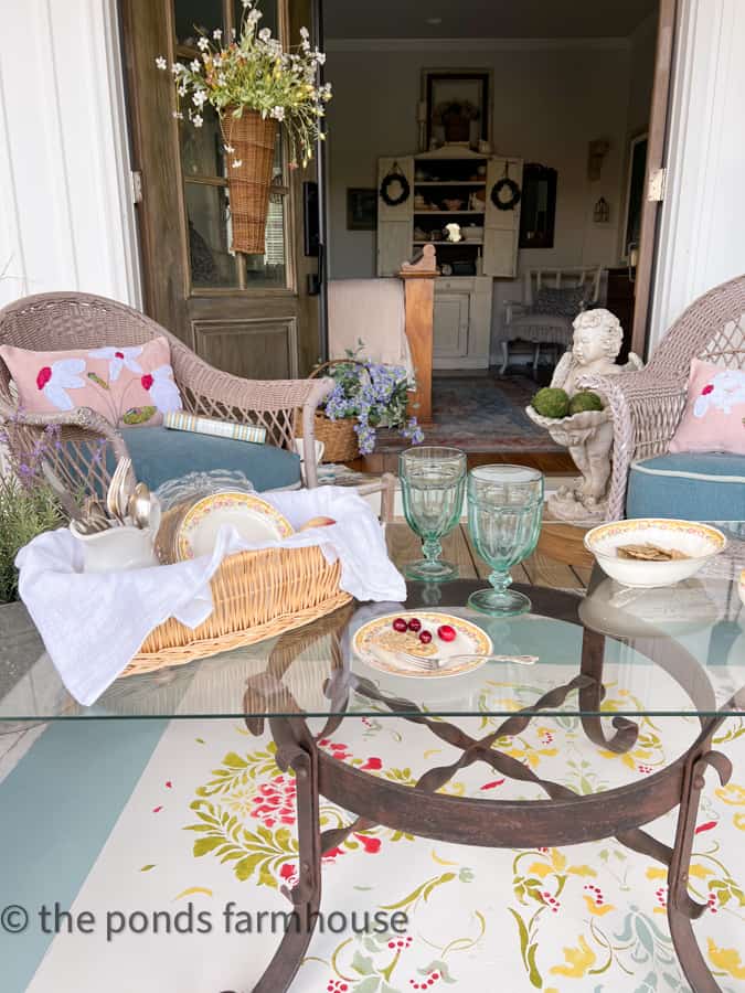 Coffee Table for Front Porch sitting ideas with vintage dishes and hand painted rug, DIY pillows and wicker chairs.  
