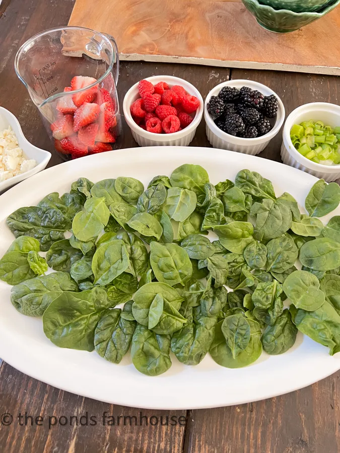 Add bed of fresh spinach to a large platter with fresh fruits chopped.