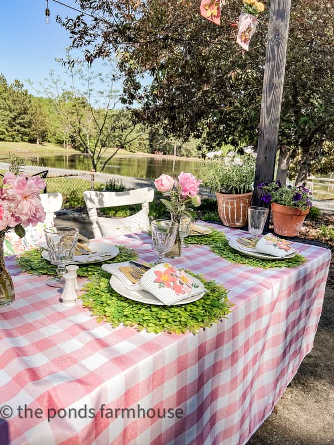 Pink and white tablecloth with greenery placemats for Mother's Day Luncheon Ideas for the tablescape.