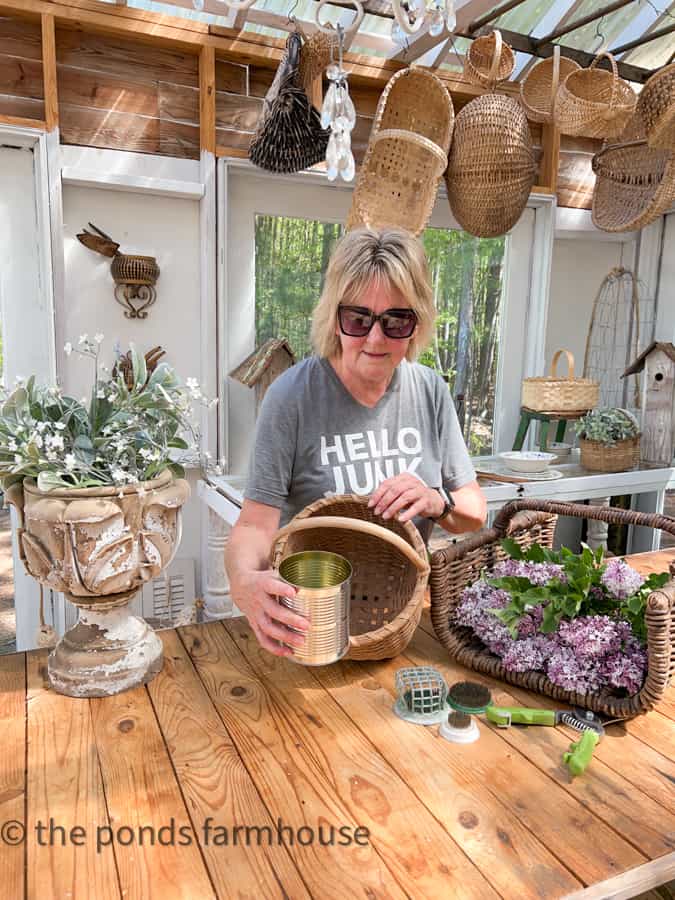 Use recycled tin can to add water to a basket for a flower arrangement in the greenhouse.