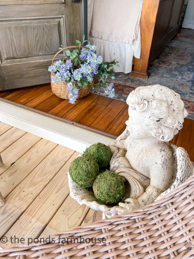 Basket of lilacs and angel with moss balls for front porch sitting decor. 
