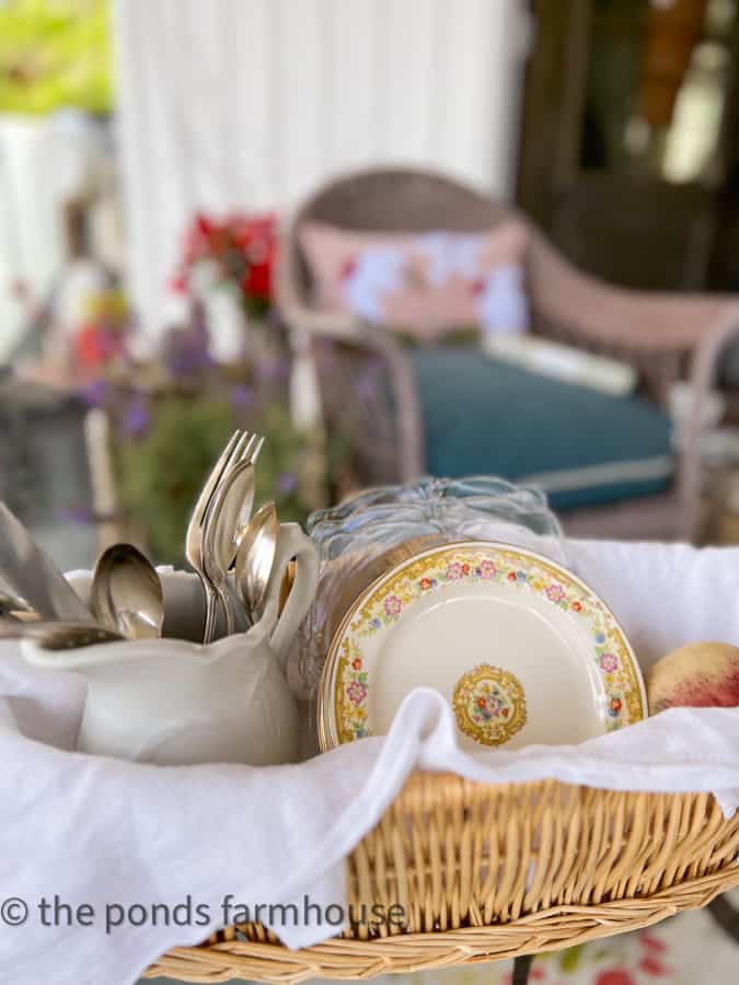 Vintage dinnerware and silverware on coffee table with hand painted DIY Rug on porch.  