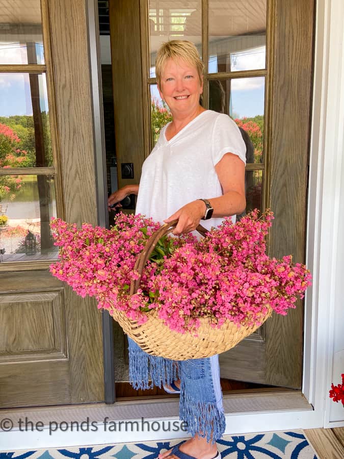 Handmade woven basket filled with fresh crept myrtle blooms on front porch.