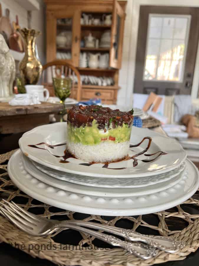 Beautiful presentation with poke tuna stack on white plate with balsamic glaze drizzle.