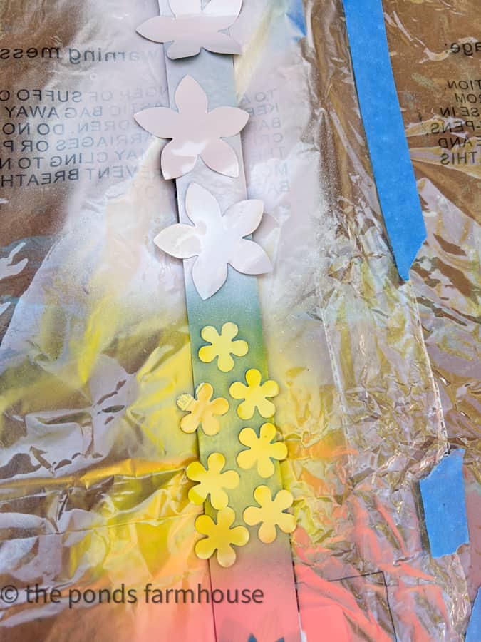 Spray paint flowers to make DIY plant pots from recycled materials.  