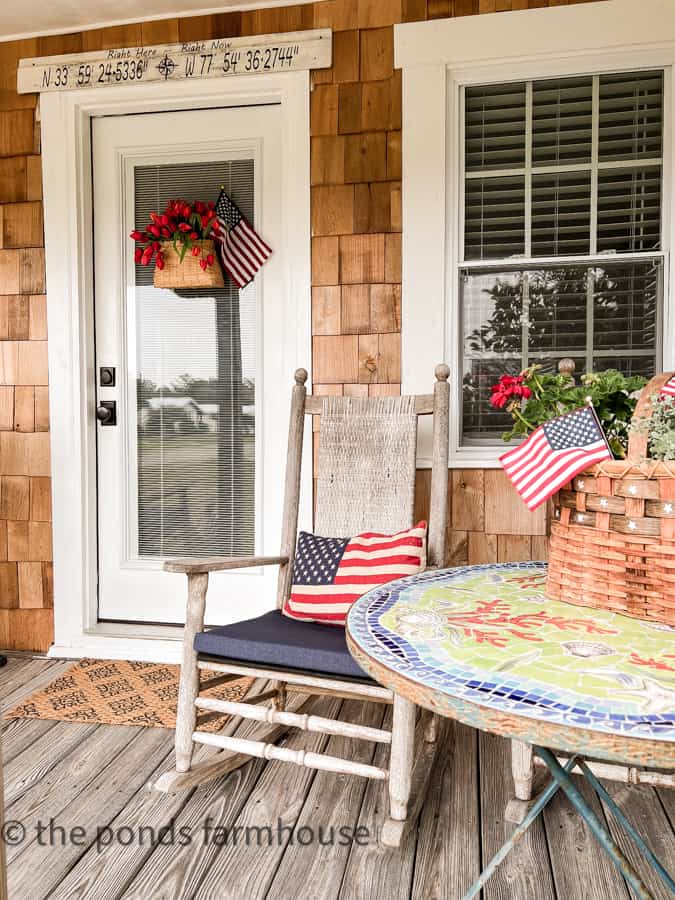 Coastal Cottage Porch decorated for the 4th of July with pillows and flags.  Patriotic flags and pillows.