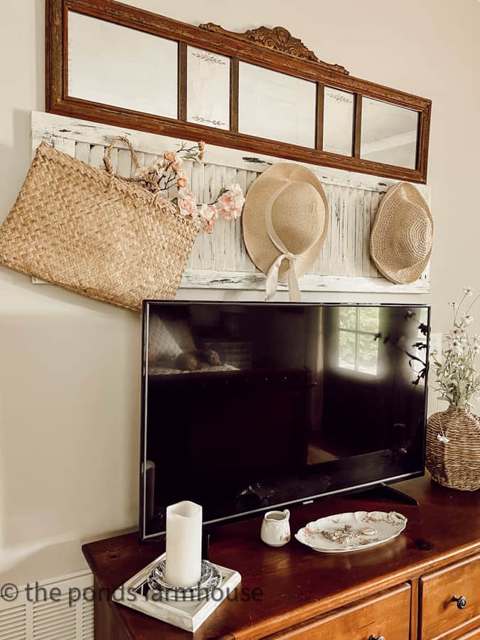 Antique mirror above straw hats over TV