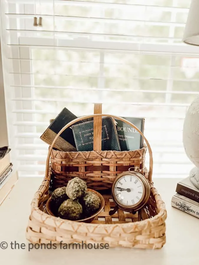 Basket filled with books, moss balls and old clock.  