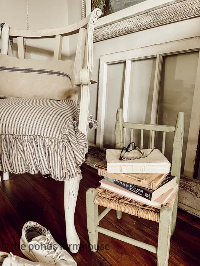 Childs chair holds books and glasses in bedroom reading corner.  