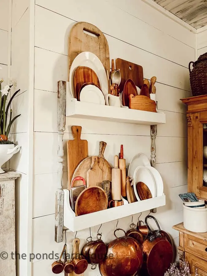 Breadboards and cutting boards fill a DIY plate rack in a modern farmhouse kitchen.