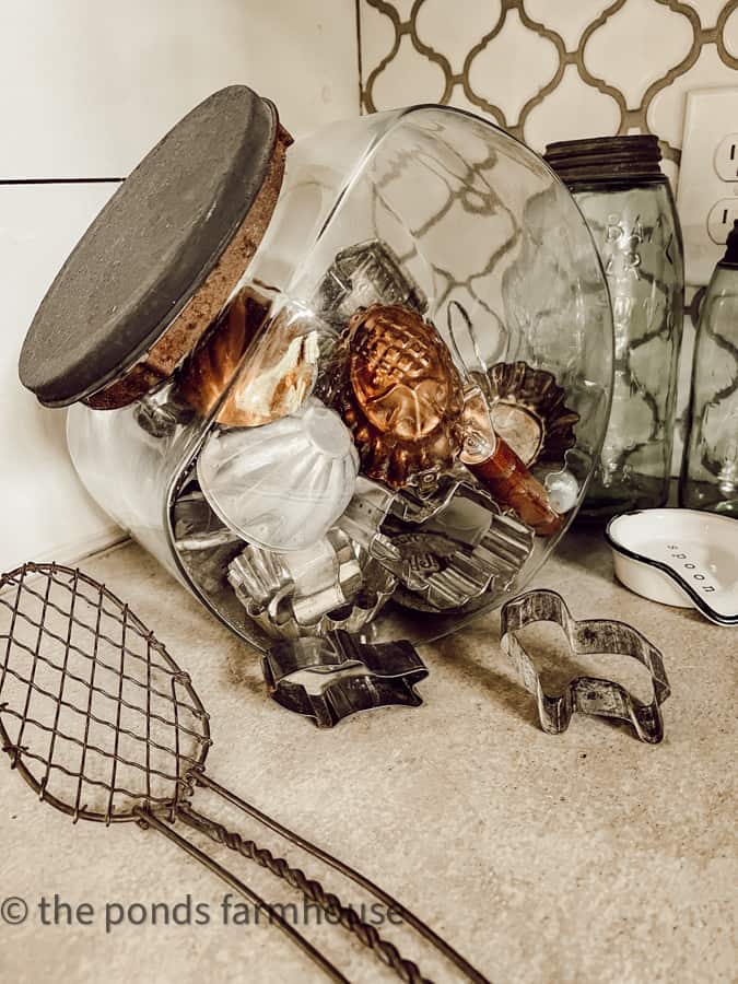 Small vintage kitchen utensils in an antique candy jar made of glass.