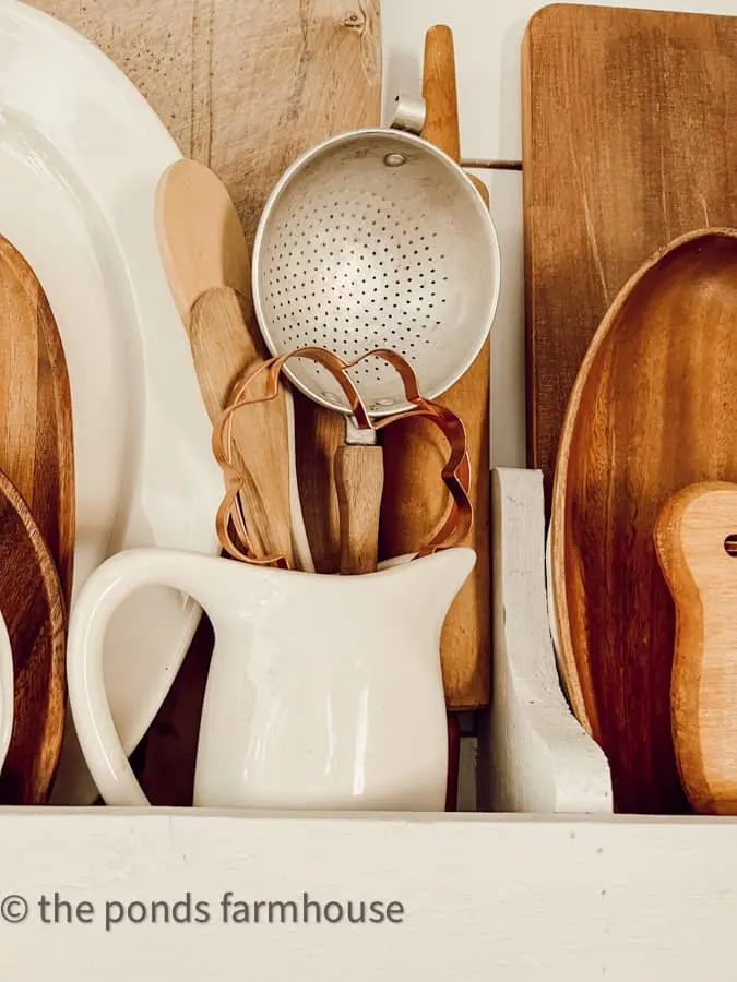 old ironstone pitcher filled with vintage kitchen utensils in a farmhouse kitchen in a DIY plate rack.