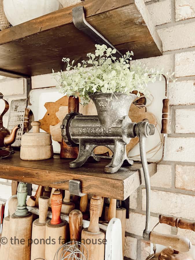 antique meat grinder on open kitchen shelf.  Vintage rolling pins in old tool box.