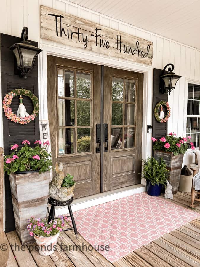 Pink spring rug at front door entry. Faux galvanized planters by front door with flowers.