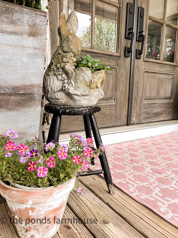 Concrete Bunny Planter and aged terra cotta pot with pink outdoor rug.
