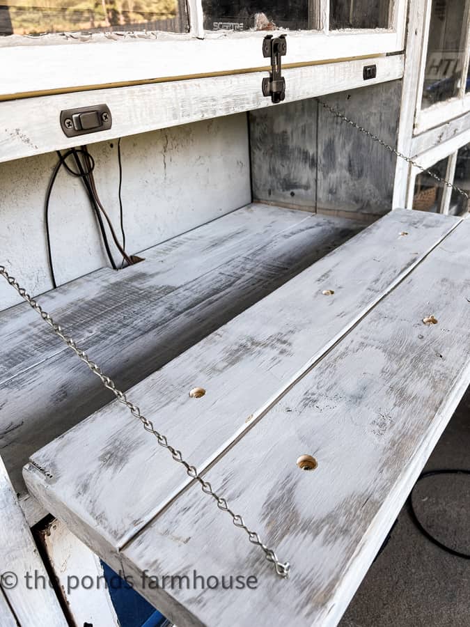 Drawer hanging open with chain in old shabby chic kitchen cabinet.