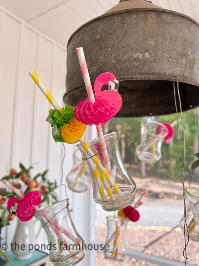 Light fixture decorated for Hawaiian themed Party with flamingo and pineapple straws in glass vases.   