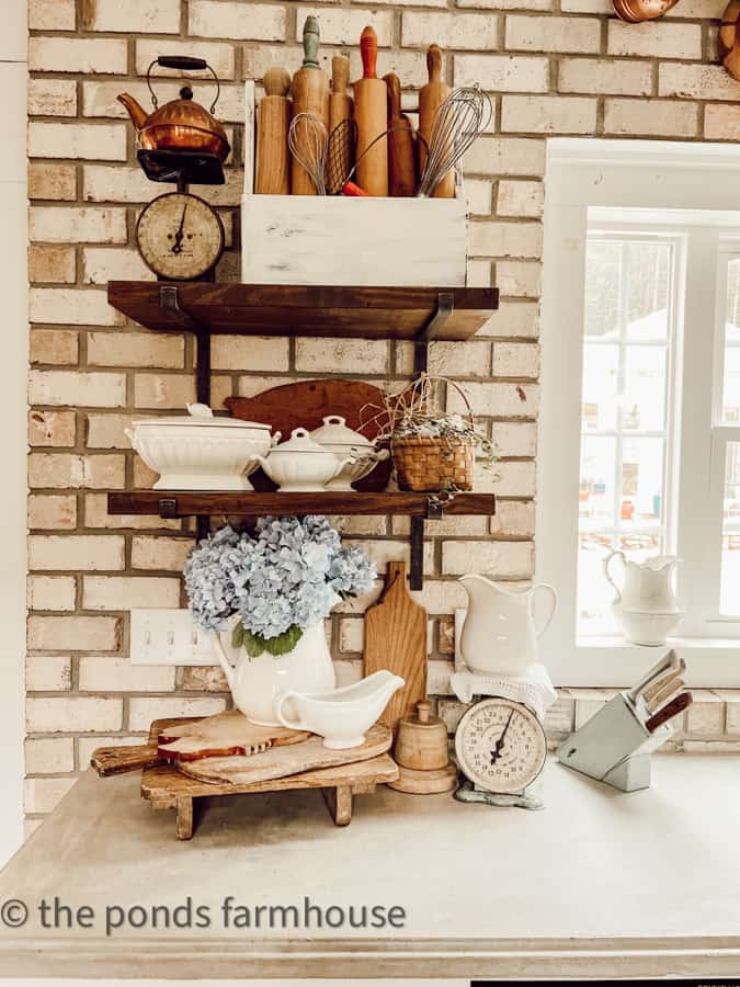 Open Kitchen Shelving with ironstone, breadboards, vintage rolling pins and old scales on countertops.