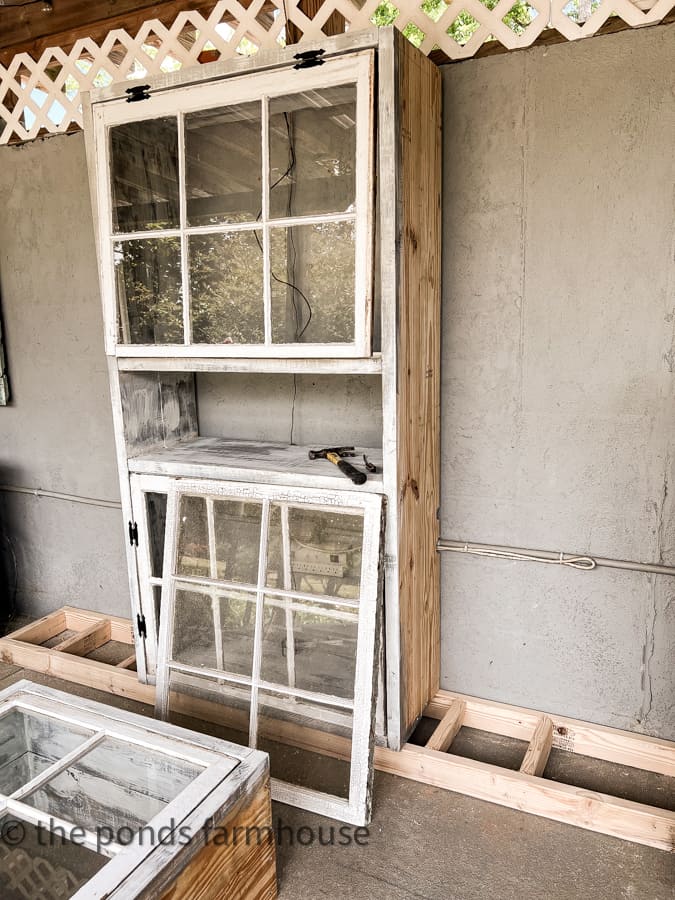 One section of rustic kitchen cabinet with reclaimed windows. Unfinished at this point. Base got cabinet on floor.