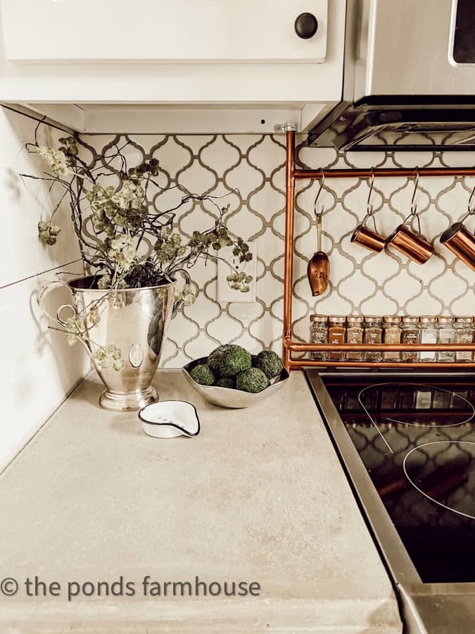 Styling vintage silver trophy urn with moss stems on farmhouse kitchen concrete countertops.  